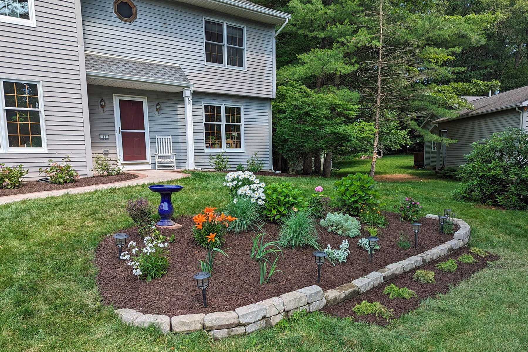 Thumbnail of after image of completed plant bed with mulch, stone, and newly planted trees
