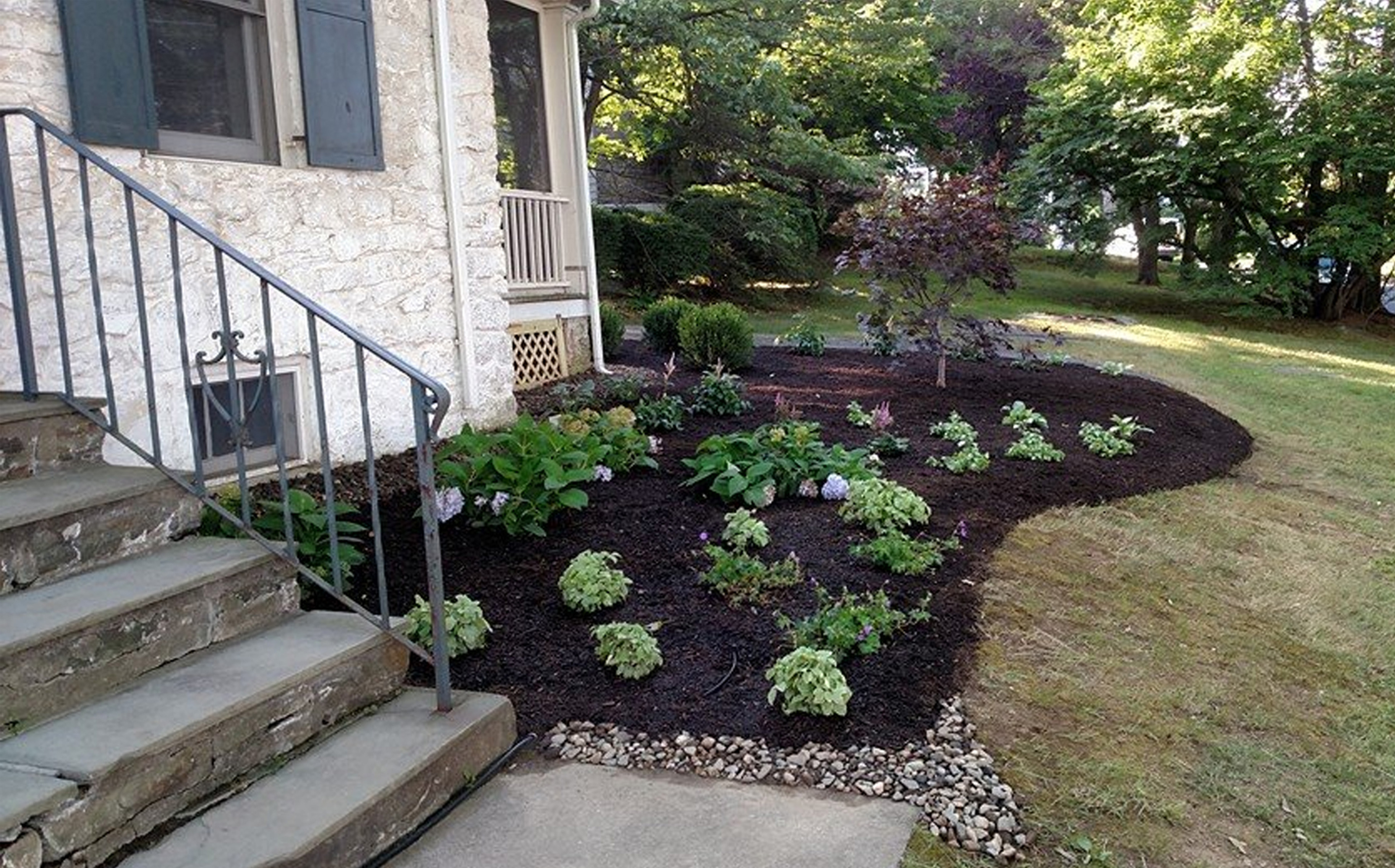 Thumbnail of completed plant bed, on the corner, with mulch and stone