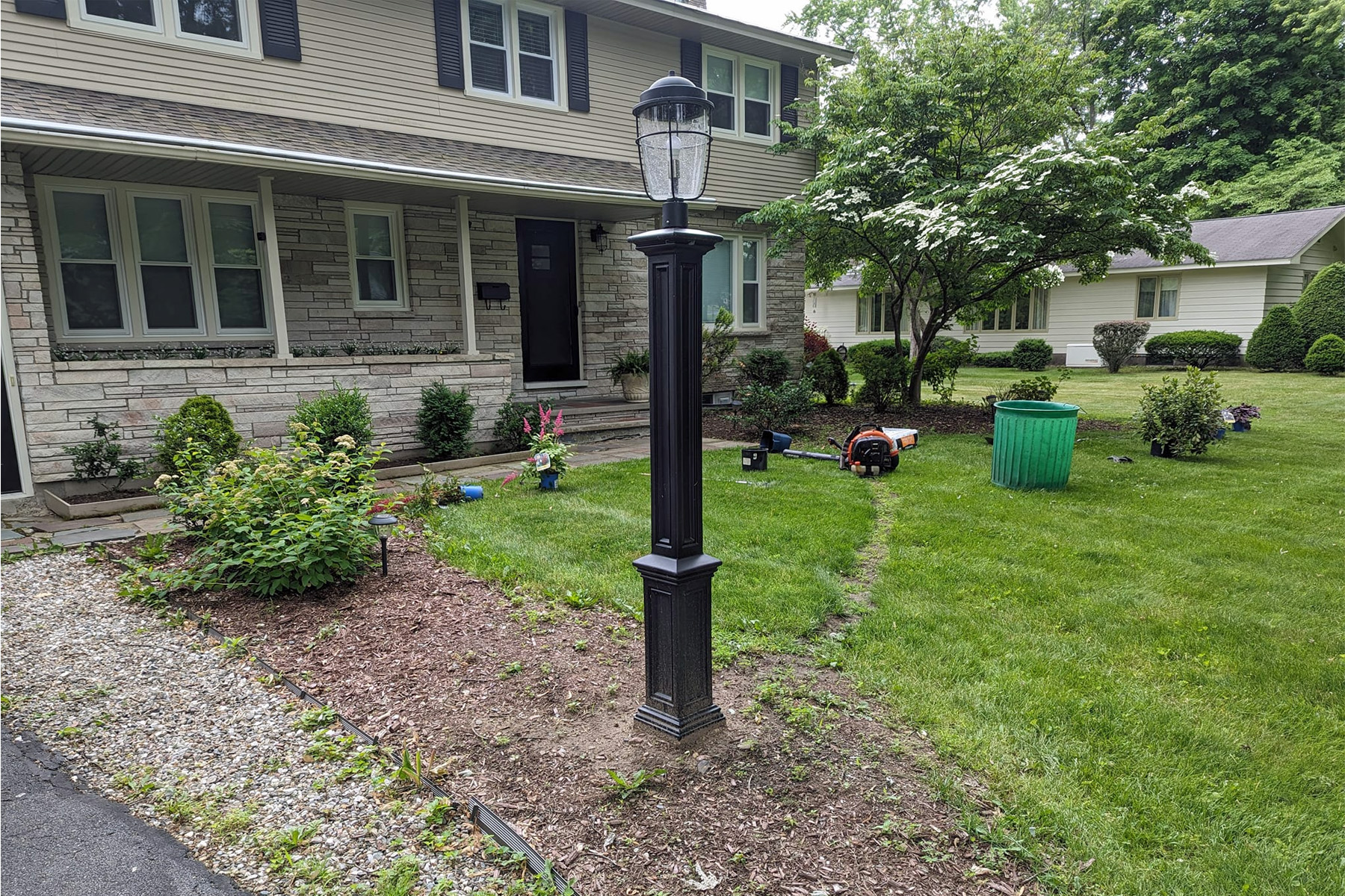 Thumbnail of an overgrown stone retaining wall and tree mulch beds