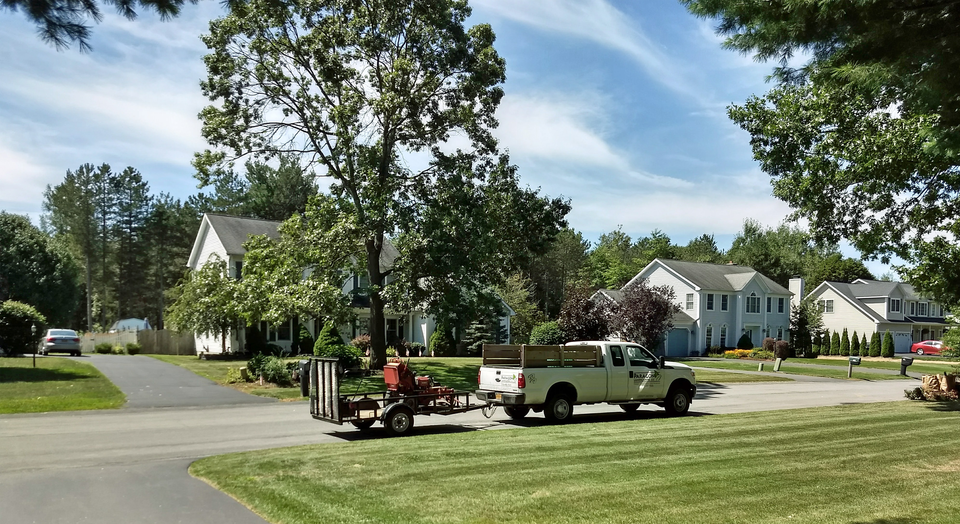 A freshly mowed lawn with my work truck and trailer holding a zero-turn mower