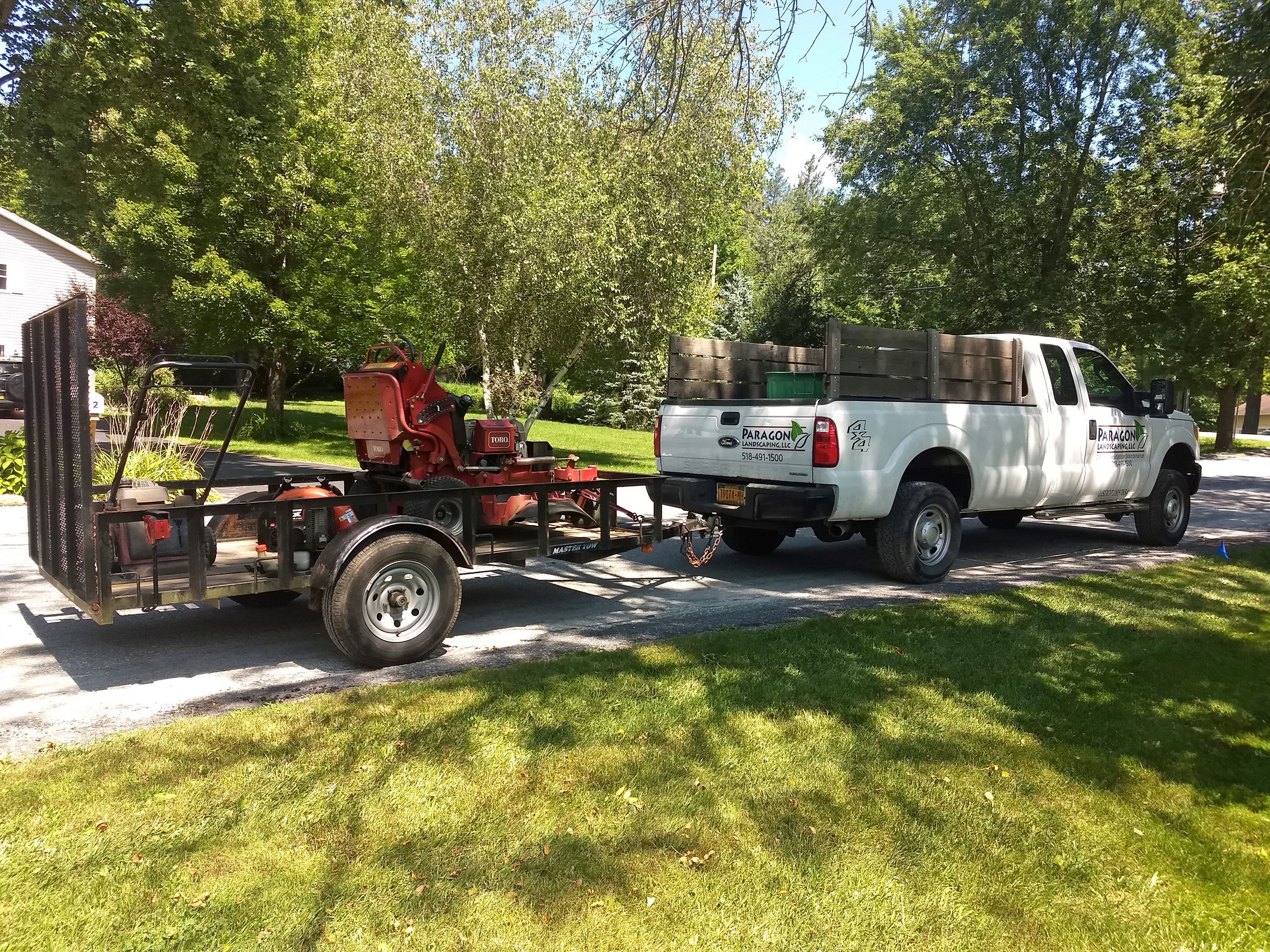 Thumbmnail image of the Paragon Landscaping work truck with a mower on a trailer attached to the hitch